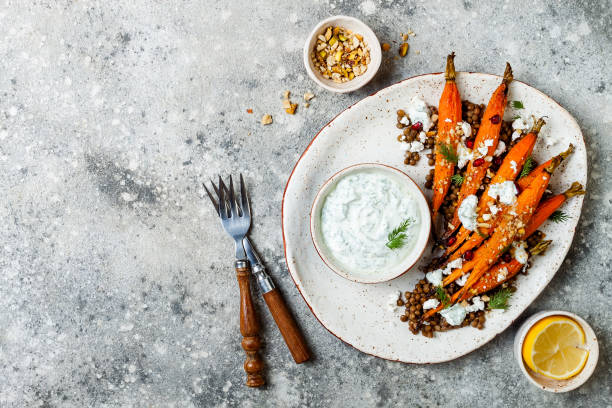 istock Roasted carrots lentil salad with feta, herb yogurt and dukkah on a light concrete background. Vegetarian food. Top view, flat lay 997745820
