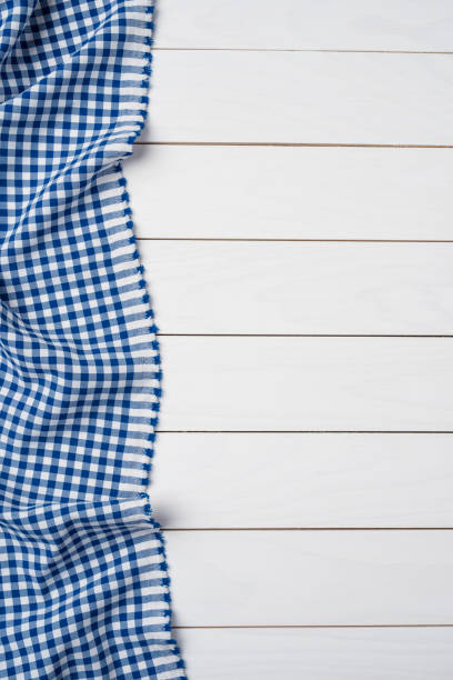 istock Blue checkered tablecloth on an old wooden table. Close up 997746828