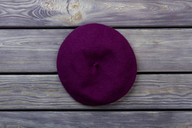 istock Purple beret hat on dark wood background. 997750124