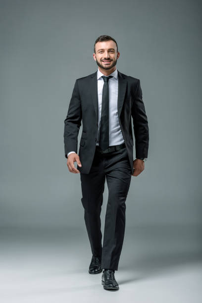 istock smiling handsome businessman walking on grey 997750776