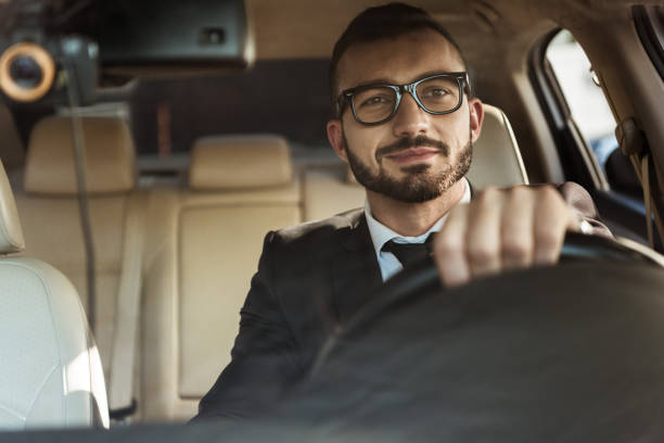 istock handsome cheerful driver in suit driving car 997750898