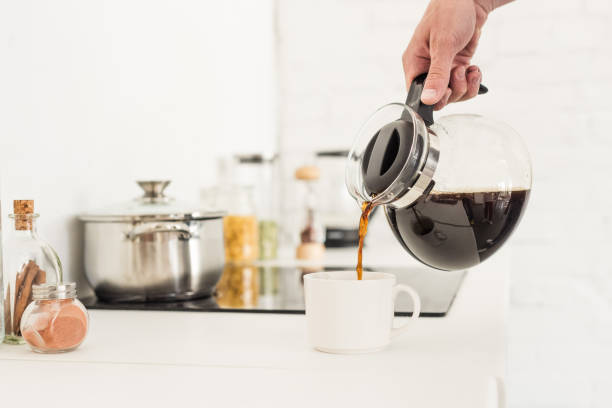 istock cropped image of man pouring coffee into cup from coffee maker at kitchen 997750994