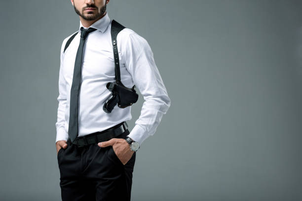 istock cropped image of security guard standing with gun isolated on grey 997754458
