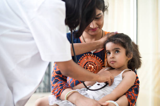 Sick girl at a check up with her mother Mother with sick daughter being examined by doctor india hospital stock pictures, royalty-free photos & images