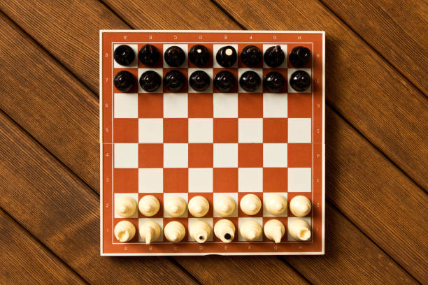 istock Black and white chess on a chessboard on a wooden table. The view from the top. Chess game concept 997785214
