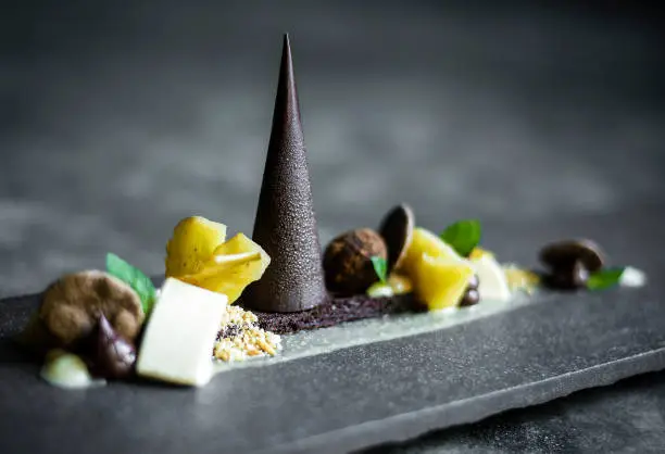 Photo of gourmet modern creative chocolate cake and dried fruit dessert dish on slate