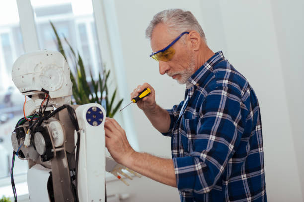 istock Serious elderly man standing near the robot 997790290