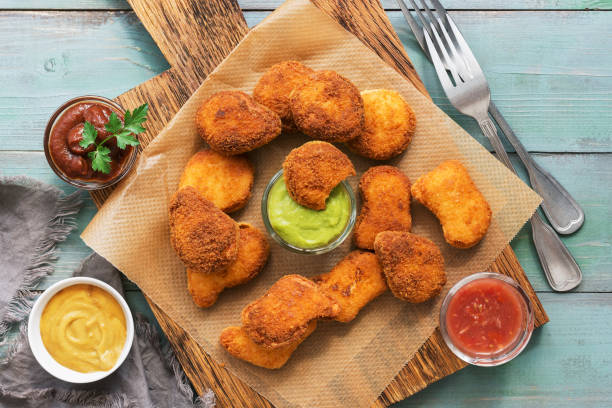 istock Chicken nuggets on a cutting board with a variety of sauces, rustic background. Top view. 997807286