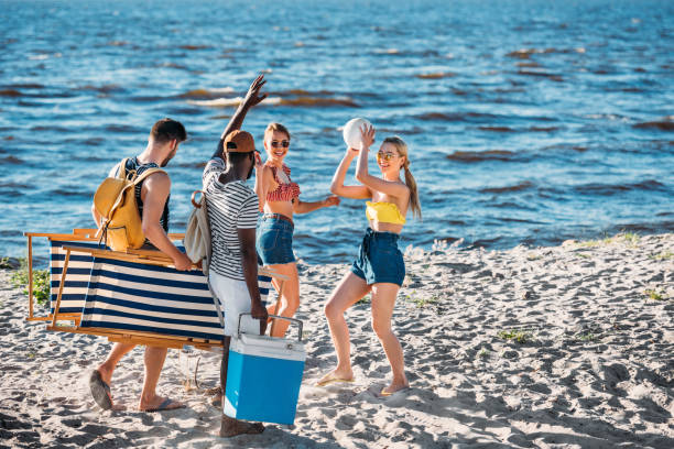 istock happy young multiethnic friends with beach items smiling each other on sandy sea coast 997809596