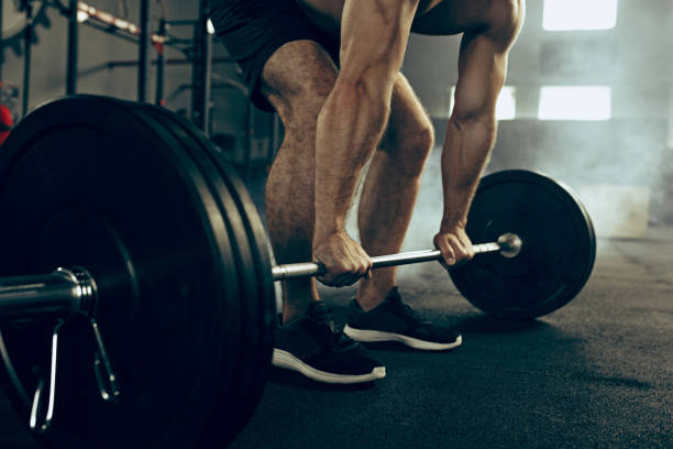 istock Fit young man lifting barbells working out in a gym 997817344