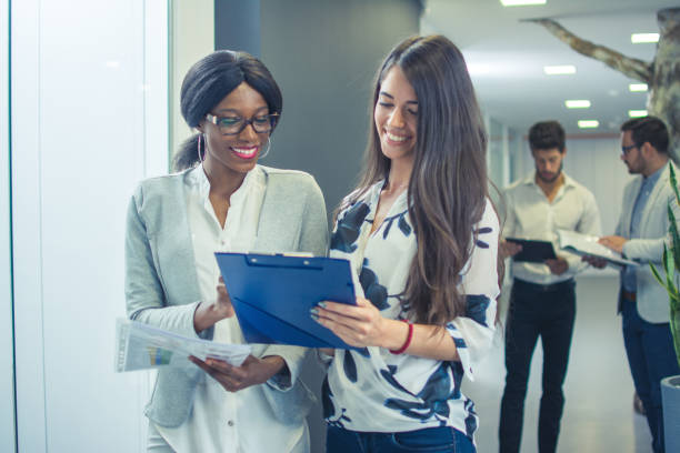 istock Two young business women talking about documents in office lobby. 997838714