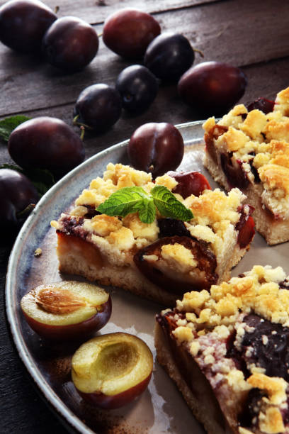 istock Rustic plum cake on wooden background with plums around. 997839274
