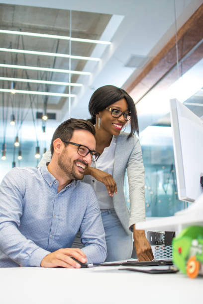 young woman and man working together on desktop pc in the modern office - contemporary friendship businessman business imagens e fotografias de stock