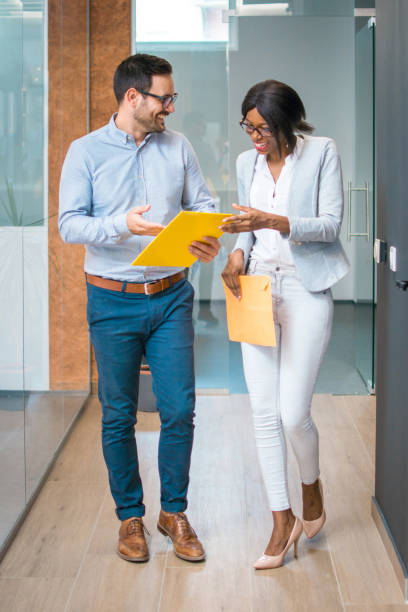 istock Two business people walking and discussing paperwork indoors 997839874