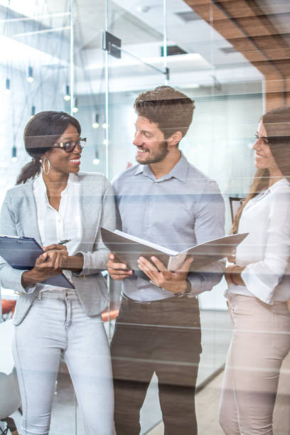 istock Group of successful businesspeople talking together over paperwork while standing in an office; 997840104