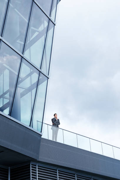 istock Businessman Stands Outside Modern Office Building 997840408