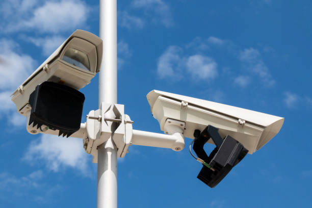Two security cameras in front of blue sky