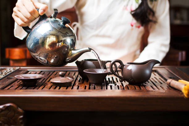 woman cleaning tea cups and pots with boiled water, tea ceremony - tea cup cup old fashioned china imagens e fotografias de stock