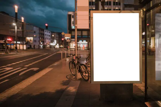 A blank billboard on a bus station at night
