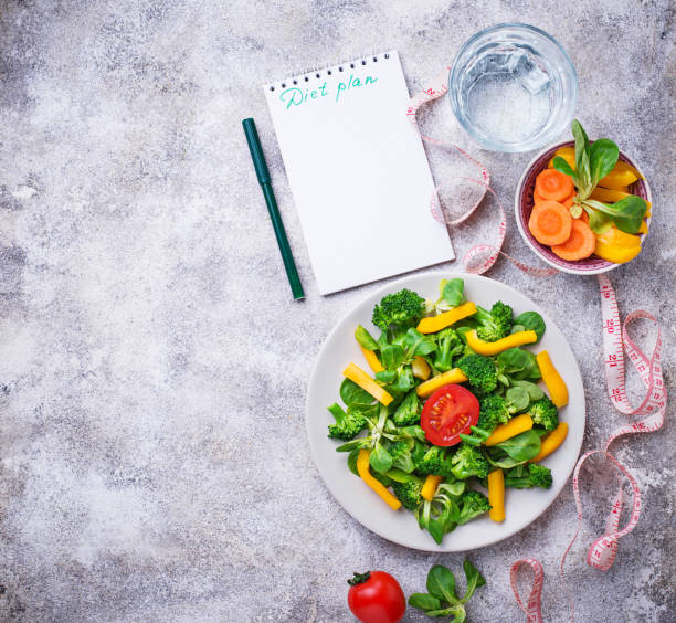 istock Healthy vegetable salad, water and measuring tape 997941444