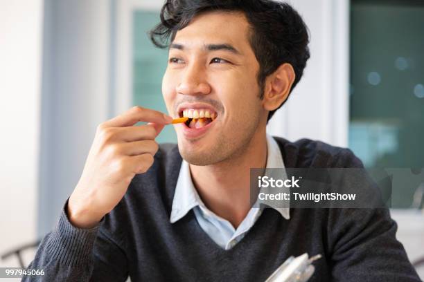 One Young College Students Adult Male Taking A Break Sat Eating Snack With Happiness Stock Photo - Download Image Now