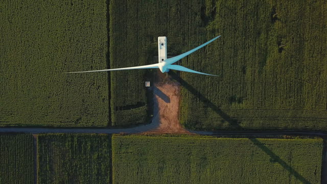 Aerial view passing directly above a wind turbine in agricultural field