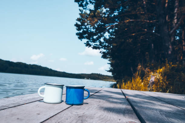 istock two metal cups with tea. river on background. 997953208