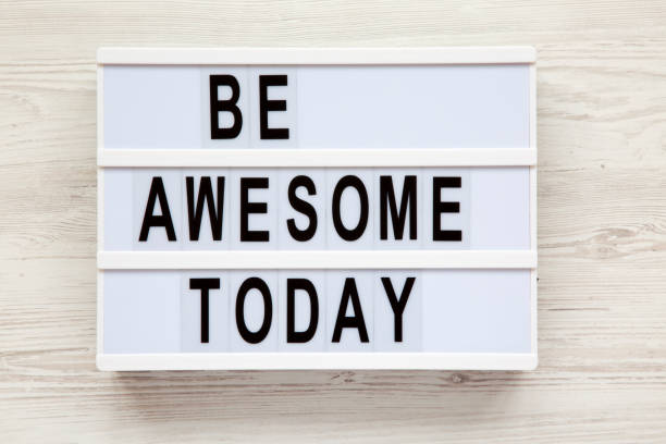 istock 'Be awesome today' word on lightbox over white wooden background, from above. Closeup. 997965258