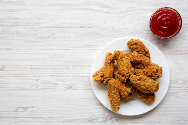 istock Chicken wings on a round white plate with sauce over white wooden surface, view from above. Overhead, flat lay, top view. Copy space and text area. 997965286