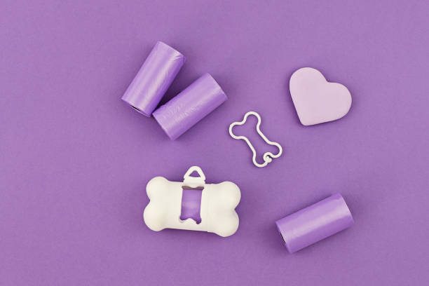 Pet dog waste poopbag dispensers and holders Pet dog waste poopbag dispensers and holders, bags for poop and white holder dispenser on violet background. Flat lay change dispenser stock pictures, royalty-free photos & images