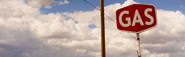 Panoramic photo of a gas sign on a cloudy day.
