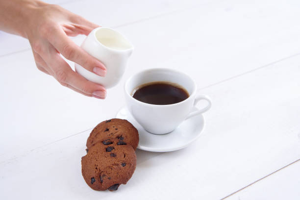 istock A woman's hand pours milk into coffee. 997972254