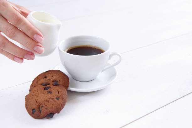 istock A woman's hand pours milk into coffee. 997972256