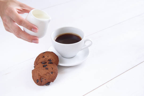 istock A woman's hand pours milk into coffee. 997972260