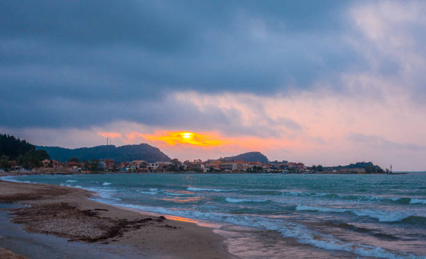 istock The sun is setting down. Infrastructures built near the coastline. Mountain ranges at the back of the houses. Scenic view of sunset and waves shoaling in the shore. Home by the sea. 997979884