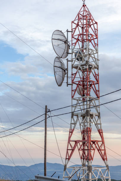 istock Transmission lines passing through broadcast tower. Satellite disk mounted in the microwave antenna. Wooden electrical post connecting coaxial cables. Local cell site. Cable network provider. 997980806