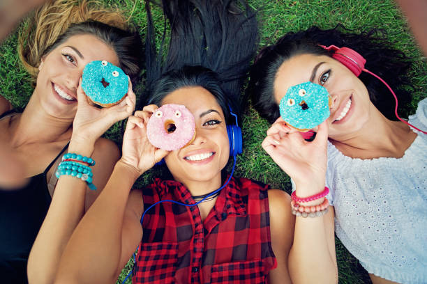 istock Happy girlfriends are taking a selfie/making video call with colorful donuts 998008352