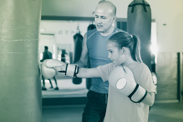 istock Young girl at boxing workout on punching bag 998067762