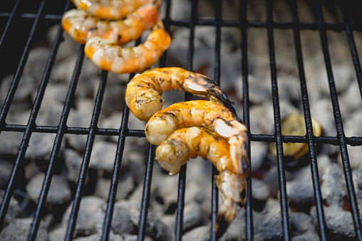 Arranged low carb shrimp cooking over a charcoal grill.