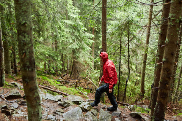 istock Man with raincoat hiking on a trail 998078088
