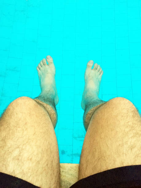 istock Man dipping his feet in a pool during summertime on vacation 998101256