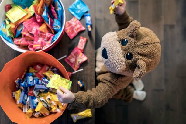 Cute Baby Boy inside Bear Costume Eating or Grabbing Candies Cute Baby Boy inside Bear Costume Eating or Grabbing Candies at Halloween halloween treats stock pictures, royalty-free photos & images