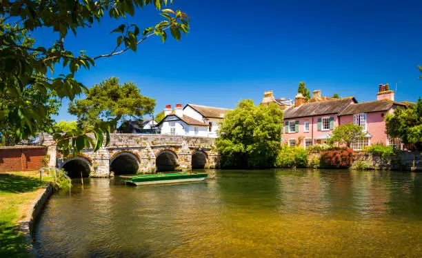 A stone bridge spans the River Avon Christchurch Dorset England on a hot summer day