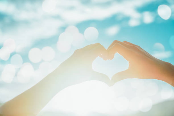 istock Woman hand do heart shape on blue sky. 998168810