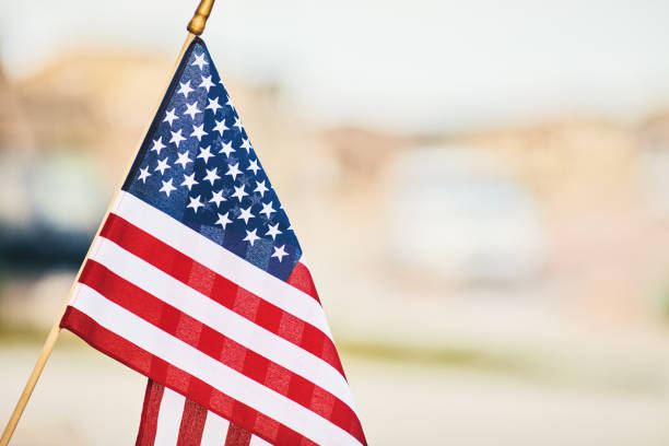 lebendige amerikanische flagge im sommersonnenschein mit defokussierten straße - flag day stock-fotos und bilder