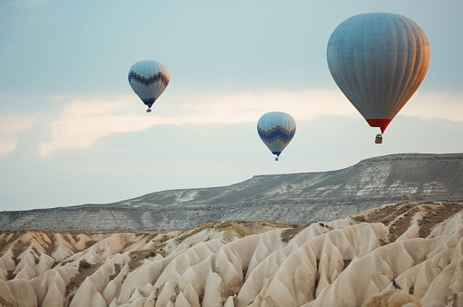Three hot air balloons flying over the rocks of Cappadocia, Turkey