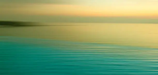 Blurred background of refraction in water. Panoramic dramatic view of Infinity Swimming Pool with sunset on the sea at twilight times.