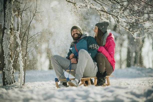 istock Cheerful couple having fun while sleighing on a snow in nature. 998207434