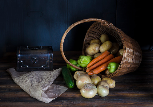 Fresh vegetable spilling out of basket.  Dark Still life concept.