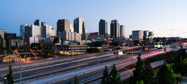 il traffico mattutino passa davanti agli edifici che riflettono la luce dell'alba a bellevue, washington - bellevue washington state foto e immagini stock